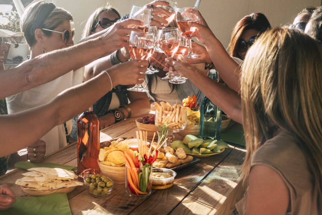 Fröhliche Geburtstagsgäste feiern bei einem festlichen Geburtstagsfrühstück, sitzen an einem Tisch und genießen zusammen Essen und gute Laune